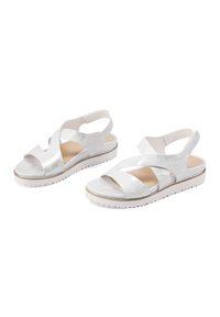 Sandali metallici argento con design a fascia incrociata, apertura sul retro, soletta imbottita e suola piattaforma bianca con finitura testurizzata.