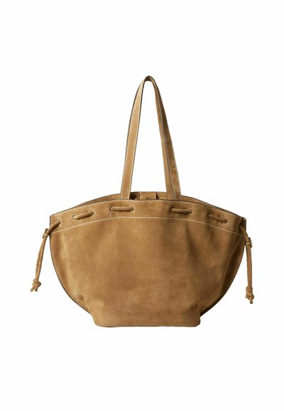 Bolso tote de ante marrón con asas largas, costuras blancas y detalles de cordón lateral sobre un fondo blanco.