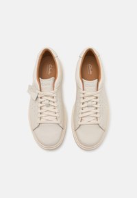 Beige leather sneakers with matching laces and subtle perforations. Rounded toe and rubber sole; features brand logo on the tongue.