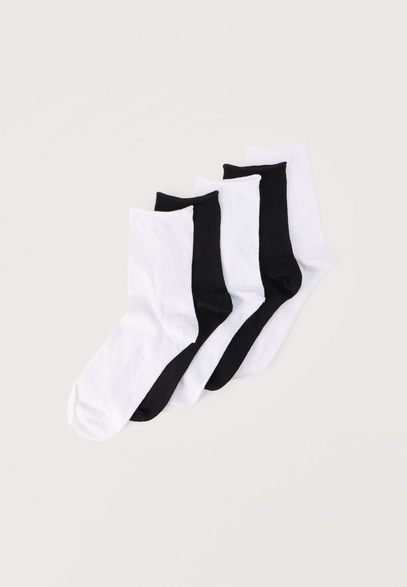 Τέσσερα ζευγάρια καλτσάκια αστραγάλου τακτοποιημένα, εναλλασσόμενα σε μαύρο και λευκό χρώμα σε απλό φωτεινό φόντο.