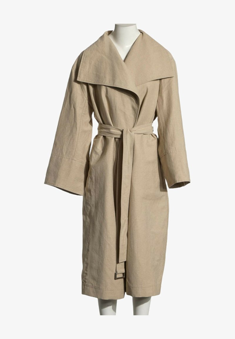 Long manteau beige avec large col, manches longues amples et ceinture assortie nouée à la taille, présenté sur un mannequin.