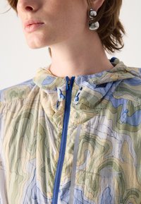 Lightweight hooded jacket in a topographic print with muted greens, blues, and beige. Features a blue zipper and toggle adjustments.