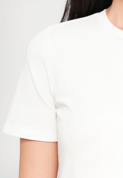 Weißes Baumwoll-T-Shirt mit rundem Ausschnitt und kurzen Ärmeln, mit einer glatten Textur und minimalistischem Design. Die Nähte sind ordentlich verarbeitet.
