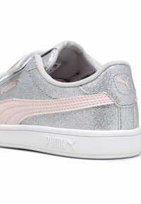 Sneaker argentati con glitter e dettagli rosa, colletto imbottito e suola bianca. Presentano il logo Puma sul lato e sul retro.