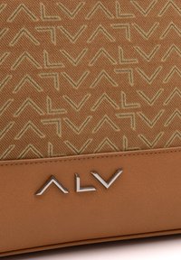 Borsa in tessuto marrone con un motivo geometrico in tonalità più chiare, con una base in pelle color cammello liscia e un accento di logo silver.