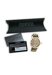 Montre Oozoo avec un boîtier en rose gold, un bracelet en cuir vert et un grand cadran gris. Comprend des cartes de garantie et une boîte noire.