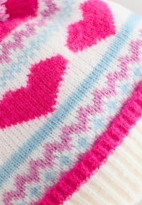 Färggath profikbrjör med en vit bas och rosa samt lila hjärtan, ljusblå zickzackmönster och en mjuk, fluffig textur.