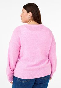 Rosa stickad tröja med avslappnad passform, med en vid halsringning och ribbade ärmslut. Mjuk textur med en något längre bakre fåll.