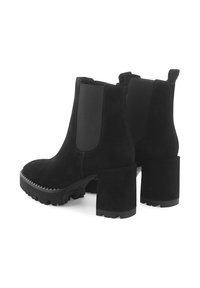 Zwarte suède enkellaarzen met elastische zijpanelen, chunky hoge hak en een getextureerde rubberen zool met zigzagpatroon.