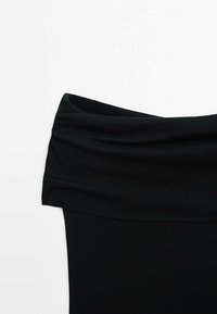 Haut noir en tissu à épaules dénudées avec un pli drapé au niveau de l'encolure, présenté sur fond blanc.