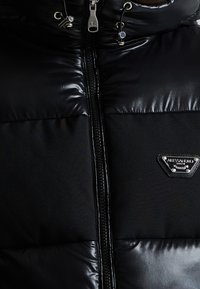 Schwarze Pufferjacke mit glänzendem oberen Abschnitt, mattem unteren Abschnitt, Reißverschluss und Markenlogo-Platte auf der linken Brust.