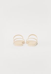 Beige flade sandaler med to tynde stropper og firkantet tåform. Glat tekstur med et minimalistisk design, velegnet til afslappet brug.