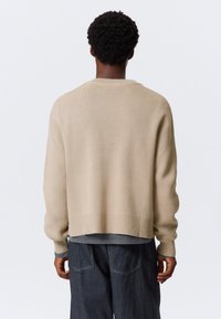 Μπεζ πλεκτό πουλόβερ με άνετη εφαρμογή, ριμπ μανσέτες και τελείωμα. Διαθέτει υφή και ραμμένους ώμους για ένα casual στυλ.