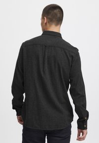Dark gray long-sleeve shirt with a button-down collar, back pleat, and cuff buttons, made from textured fabric.