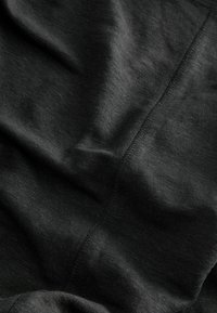 Tessuto nero con una superficie liscia e morbida, caratterizzato da sottili variazioni di tonalità. Include cuciture visibili e una finitura leggermente lucida.