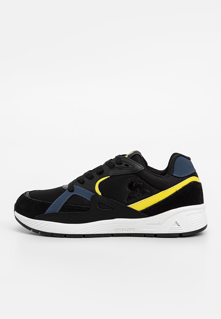 Black athletic shoe featuring a mesh upper with suede accents, blue and yellow detailing, and a white rubber sole with textured grip.