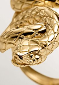 Anillo con forma de serpiente en oro que presenta escamas y texturas intrincadas. El diseño se envuelve, con una cabeza de serpiente detallada y un acabado brillante.