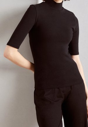 Zwart, nauwsluitend shirt met een hoge hals en korte mouwen, gemaakt van gladde stof, gecombineerd met bijpassende zwarte broek, afgebeeld tegen een neutrale achtergrond.