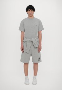 Light gray cotton t-shirt and shorts, both with a relaxed fit. T-shirt features a small logo, and shorts have a logo on the left leg.