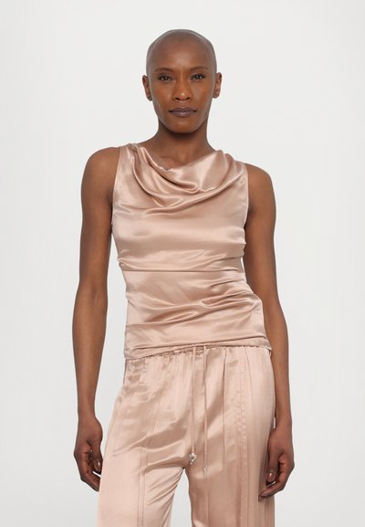 Top in satin rosa chiaro con scollatura a collo di cigno e vita arricciata, abbinato a pantaloni in satin coordinati con cordino regolabile e pieghe.