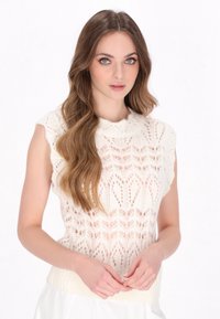 Strickästliches ärmelloses Oberteil in Elfenbein mit einem Spitzenmuster, rundem Ausschnitt und geripptem Saum. Leichte Textur mit dezentem Durchbruchsdesign.