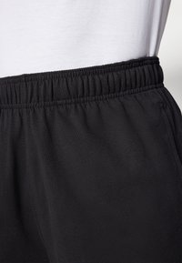 Black sweatpants with an elastic waistband, featuring a smooth texture and a relaxed fit. The fabric appears lightweight and durable.