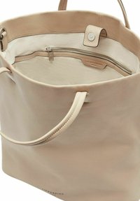 Bolso tote de cuero beige con dos asas, parte superior abierta con cierre magnético y bolsillo interior con cremallera.