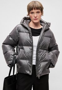 Fényes szürke színű, bélelt pufi dzseki cipzárral az elején, csatolt kapucnival és első zsebekkel. Sima textúrájú, steppelt mintázattal.