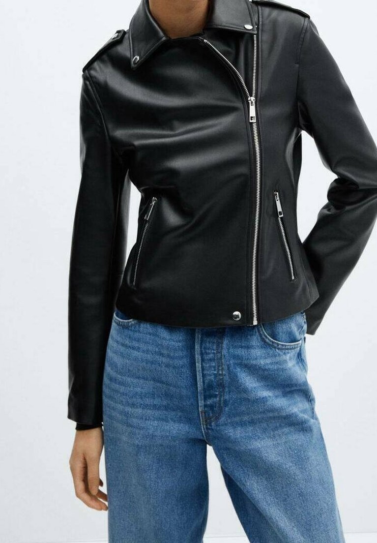 Femme portant une veste en cuir noire ajustée avec une fermeture éclair diagonale et des poches zippées, associée à un jean bleu taille haute.