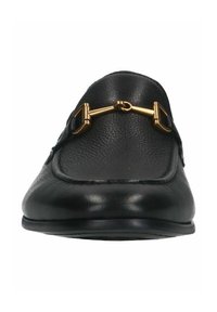 Black leather loafer with rounded toe, flat sole, and a gold metal accent across the top. Texture is smooth with visible stitching details.