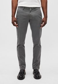 Pantalons en coton gris avec une coupe ajustée. Dotés de poches latérales et d'un éclat subtil. Assortis à des chaussures noires à enfiler.