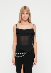 Camisole negru cu decolteu volanat, material transparent �în partea de sus, bretele ajustabile și un tiv asimetric. Asortat cu o fustă elegantă cu accente metalice în formă de stele.