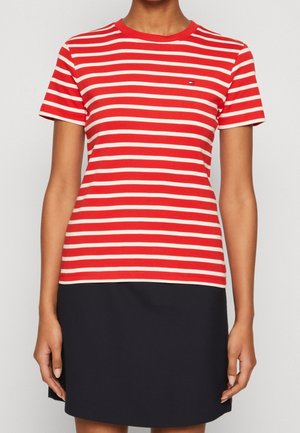 Czerwono-biała koszulka w paski z krótkimi rękawami, okrągłym dekoltem i małym detalem logo, w połączeniu z granatową spódnicą.