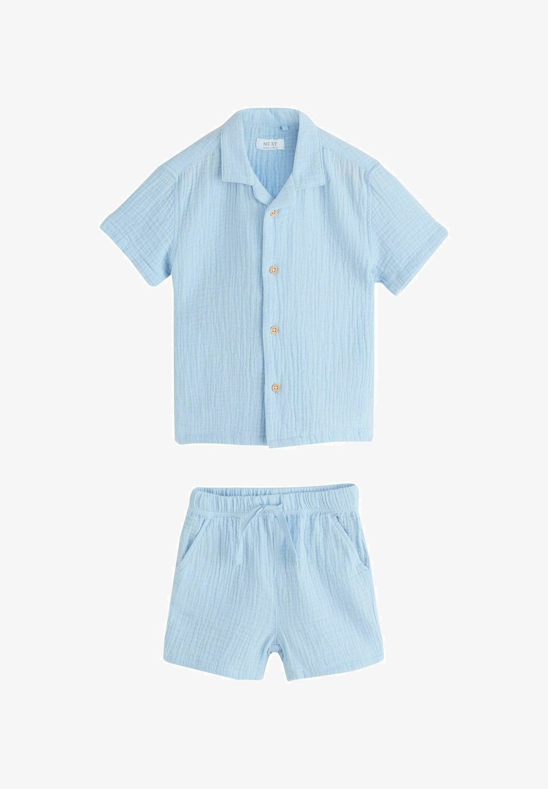 Chemise à manches courtes boutonnée en tissu texturé bleu clair et shorts assortis à taille élastique avec cordon de serrage, posés à plat sur fond blanc.