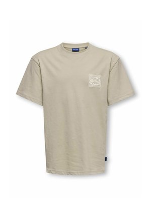 T-shirt beige à manches courtes avec col rond, avec un petit logo blanc sur le thème du surf sur la poitrine gauche et une étiquette bleue sur la couture latérale.