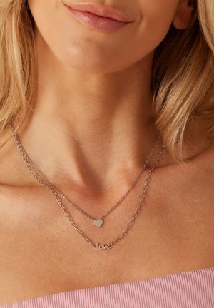 Silberne mehrschichtige Halsketten mit einem Herz-Anhänger und einem "Love"-Pendant, mit einer glatten Textur und einem zarten Kettendesign.