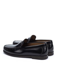 Pair of black leather men's loafers with penny strap detail, stitched moc toe, and low stacked heels on white background.