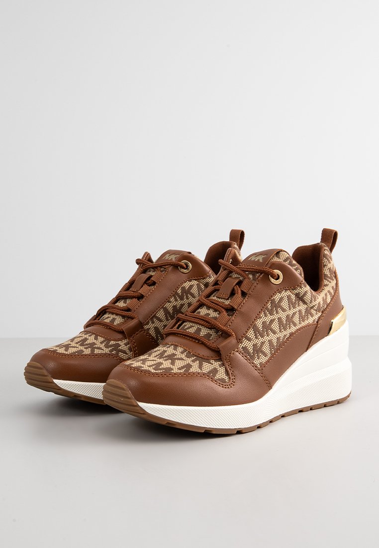 Zapatillas de cuero marrón y tela estampada con tacón cuña, detalles dorados y cierre de cordones. Superficie texturizada y cuello acolchado.