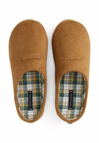 Ein Paar braune Wildlederschlappen mit kariertem Stofffutter und "Tommy Hilfiger"-Etiketten innen sowie gesticktem Markenlogo auf der Oberseite.