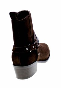 Stivali ankle in suede marrone con punta arrotondata, tacco basso impilato, decorazioni laterali a fibbia e una texture liscia.
