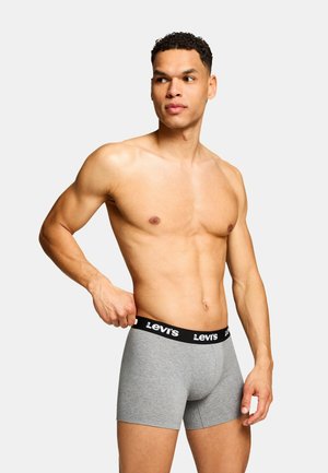 Graue Baumwoll-Boxershorts mit einem schwarzen Bund, der das Levis-Logo zeigt, dargestellt an einer stehenden männlichen Figur mit nacktem Oberkörper.