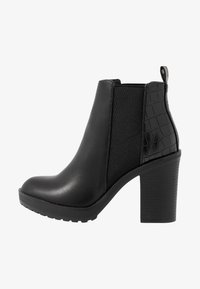 Botas negras hasta el tobillo con un acabado de cuero suave, paneles laterales elásticos, acentos con grabado de cocodrilo y un resistente tacón cuadrado.