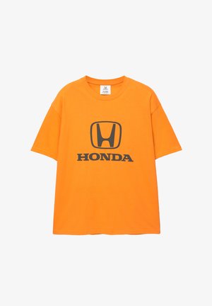 Orange bomull T-shirt med en svart Honda-logotyp och text i mitten. Korta ärmar och rund halsringning; avslappnad passform.