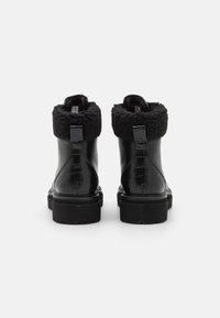 Stivali alla caviglia in pelle nera con una finitura lucida effetto coccodrillo, dotati di un morbido risvolto in shearling nero e suole in gomma nera durevoli.