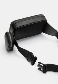 Svart syntetisk axelväska med rektangulär form, dragkedjestängning, justerbara remmar och en liten dragkedjefack på sidan.