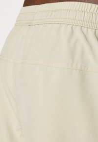Light beige shorts with an elastic waistband, featuring flat seams and a smooth, subtle sheen. Designed for comfort and ease of movement.