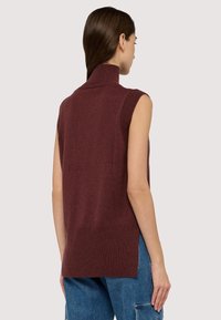 Ärmelloser Rollkragenpullover in Burgunderrot, gestrickte Textur, mit Rippdetails am Kragen und Saum sowie seitlichen Schlitzen für mehr Bewegungsfreiheit.