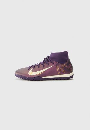 Des chaussures de sport violettes avec un col haut, une tige texturée, des accents dorés et une semelle à motif conçue pour l'adhérence.
