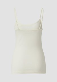 Jasnokremowy top na ramiączkach z cienkimi, regulowanymi paskami, zaokrąglonym dekoltem i bezszwowym designem. Tkanina wydaje się miękka i gładka.