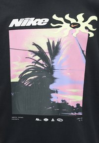 Nike logo above stylized sun with swoosh, pink and purple sky with palm trees, and small text and logos at the bottom on black background.